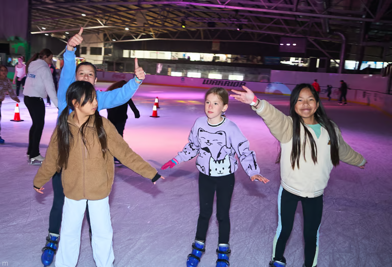 Kids ice skating at a birthday party with the Ice Arena penguin mascot