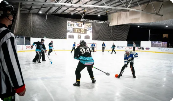 Broomball players competing on an indoor ice rink